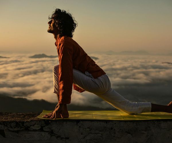Silhouette of a person in a powerful yoga warrior pose against a sunrise.